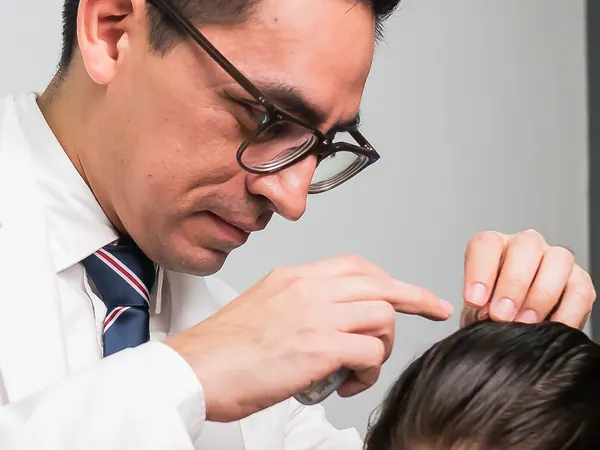 El Dr. Orozco revisa el cuero cabelludo de una niña